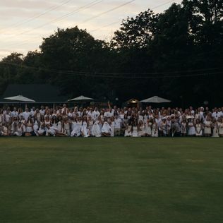 A long-shot group photo of people wearing white